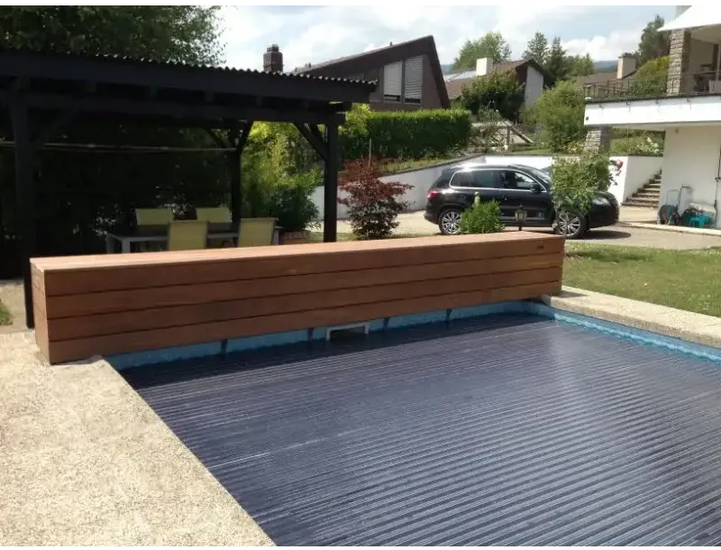 Lamelltrekk med opprulling over vannflaten – 60 x 14 mm, mørkeblå ribbet overflate, trebenk ved siden av