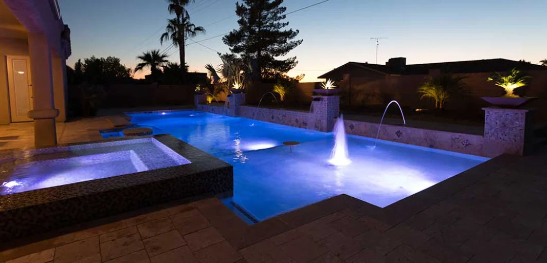 Blå upplyst ovanjordspool med central fontän och jacuzzi för sommarsäsong.