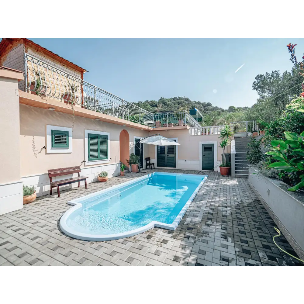 Glasfiberpool Aves med avrundad trappa och kaklad omgivning i blått vatten