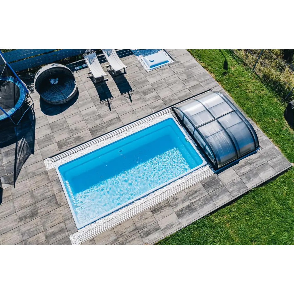 Glasfiberpool Papeete med klart blått vatten och transparent lock på grå stenplattor