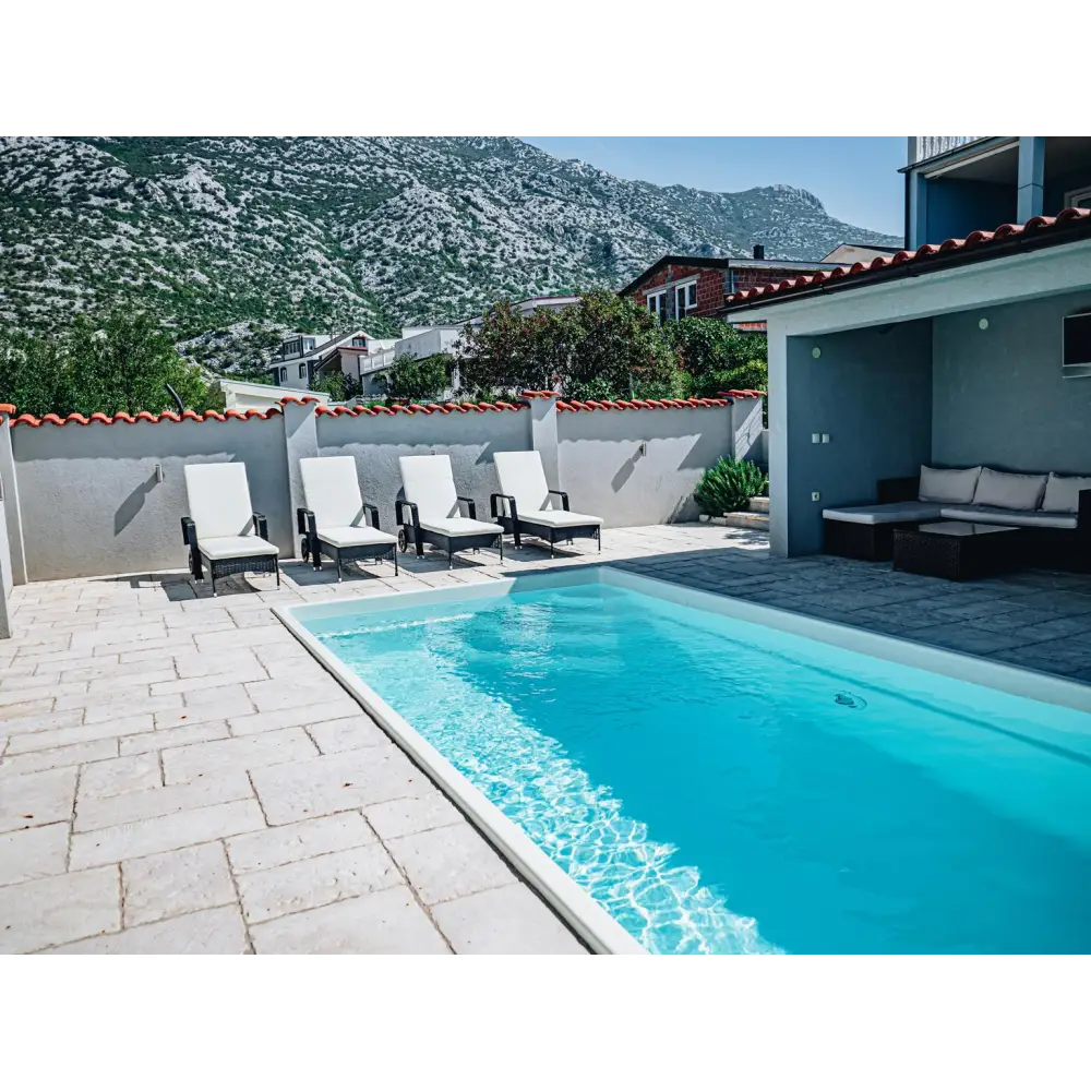 Glasfiberpool Saba med klart blått vatten och vita kaklade kanter