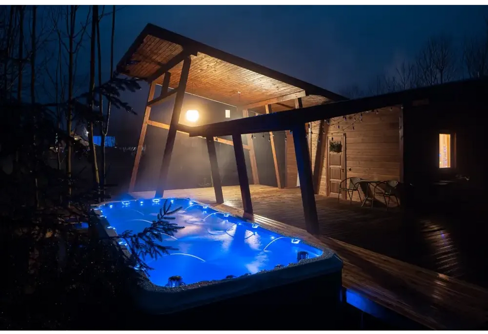 Blå upplyst PassionSpa Activity 2 Swim Spa med trädäck och täckt uteplats