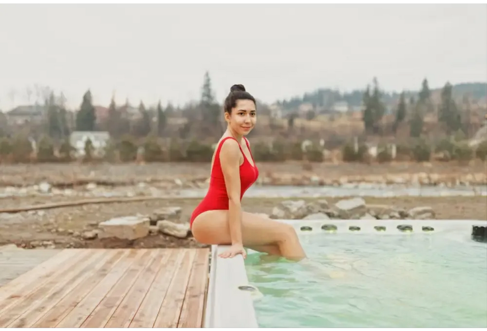 Kvinna i röd baddräkt sitter vid PassionSpa Swim Spa-kant