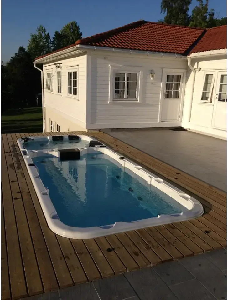 Vit PassionSpa Aquatic 3 Deep Swim Spa med blåvatten och svarta sittdynor på trädäck
