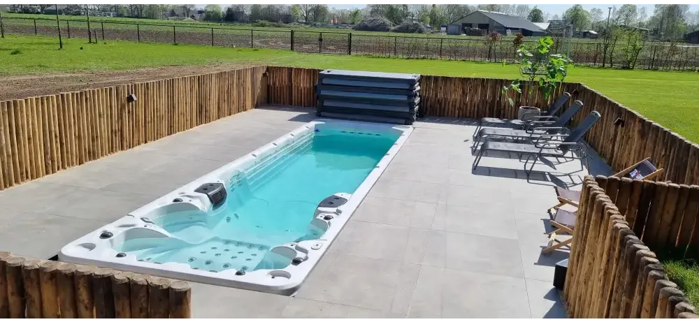 Vit PassionSpa Aquatic 6 Swim Spa – Sport Collection, vit rektangulär med turkost vatten och svarta jetstrålar, omgivet av trästaket