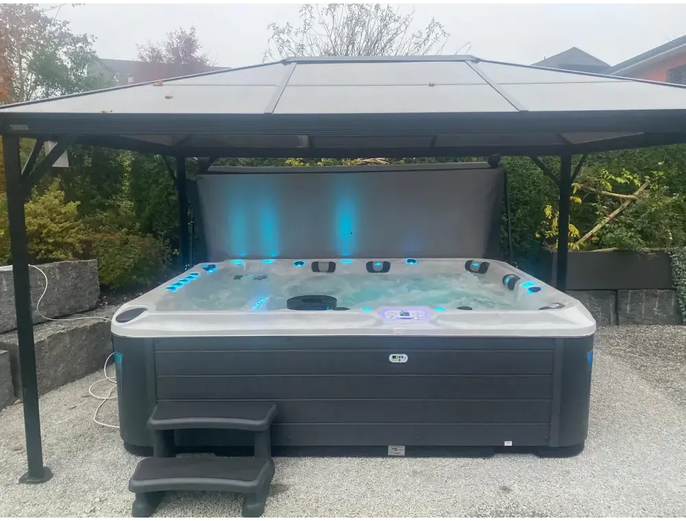 Svart och grå PassionSpa Ecstatic Mighty Wave med blå LED-belysning under tak