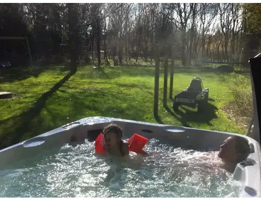 Grått PassionSpa Relax Spabad Pure Collection med bubblande vatten och två personer som slappnar av
