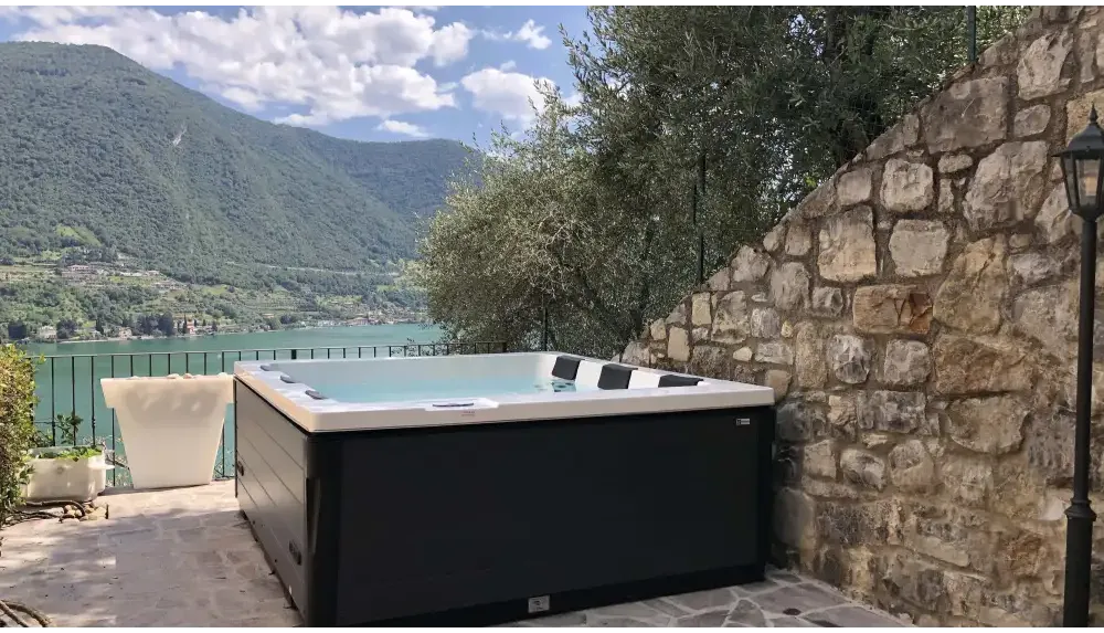PassionSpa Serene 6 eldstadsspabad i svartvit modern design mot stenvägg