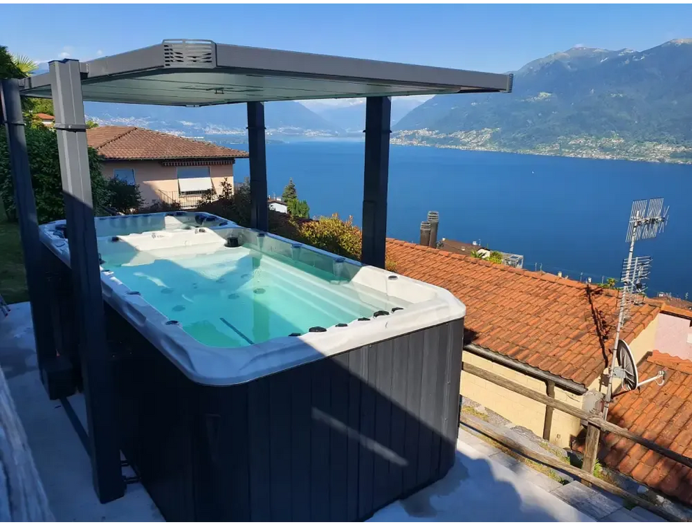 Svartvit PassionSpa Spirit Deep Swim Spa med modern tak över takterrass mot sjö
