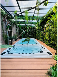 Vit PassionSpa Spirit Swim Spa – Sport Collection, vit badkar med svarta jetstrålar i grönska under transparent tak