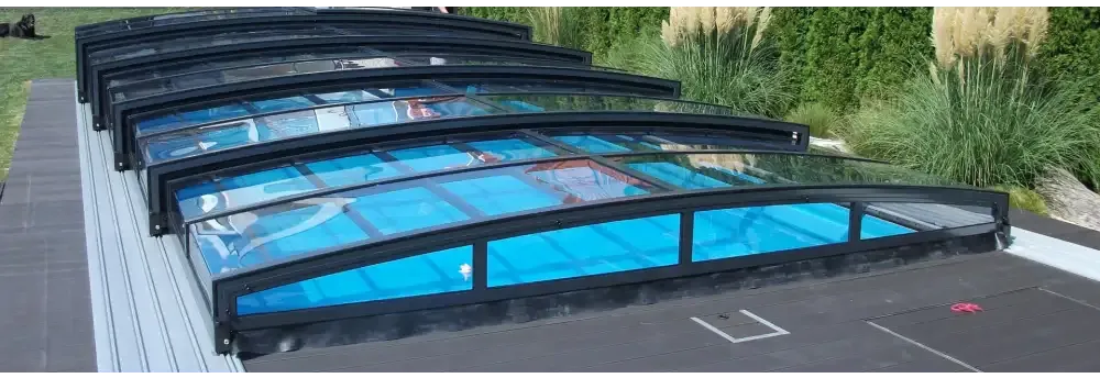 Pooltak special med böjd glasdesign och svart ram över blå poolvatten