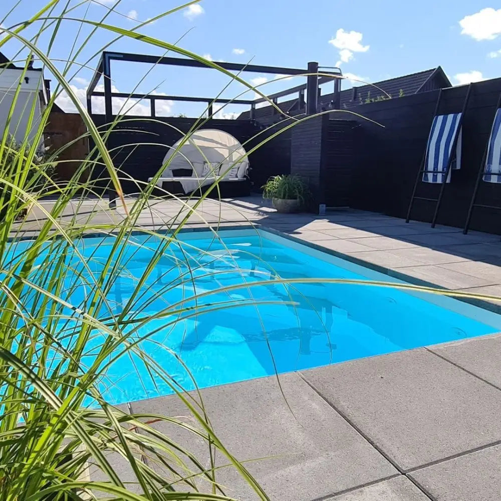 Pooltime Exklusiv 12mm rektangulär pool med kristallklar blå vatten, kaklade kanter och grönska