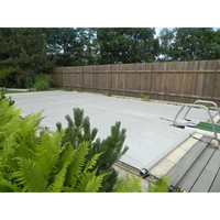 Grå pooltäckning med metallram, inkl handenhet, gröna växter i förgrunden